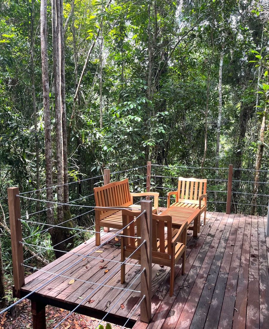 Deck de madera con mesa y sillas elevado entre los árboles de la Mata Atlántica