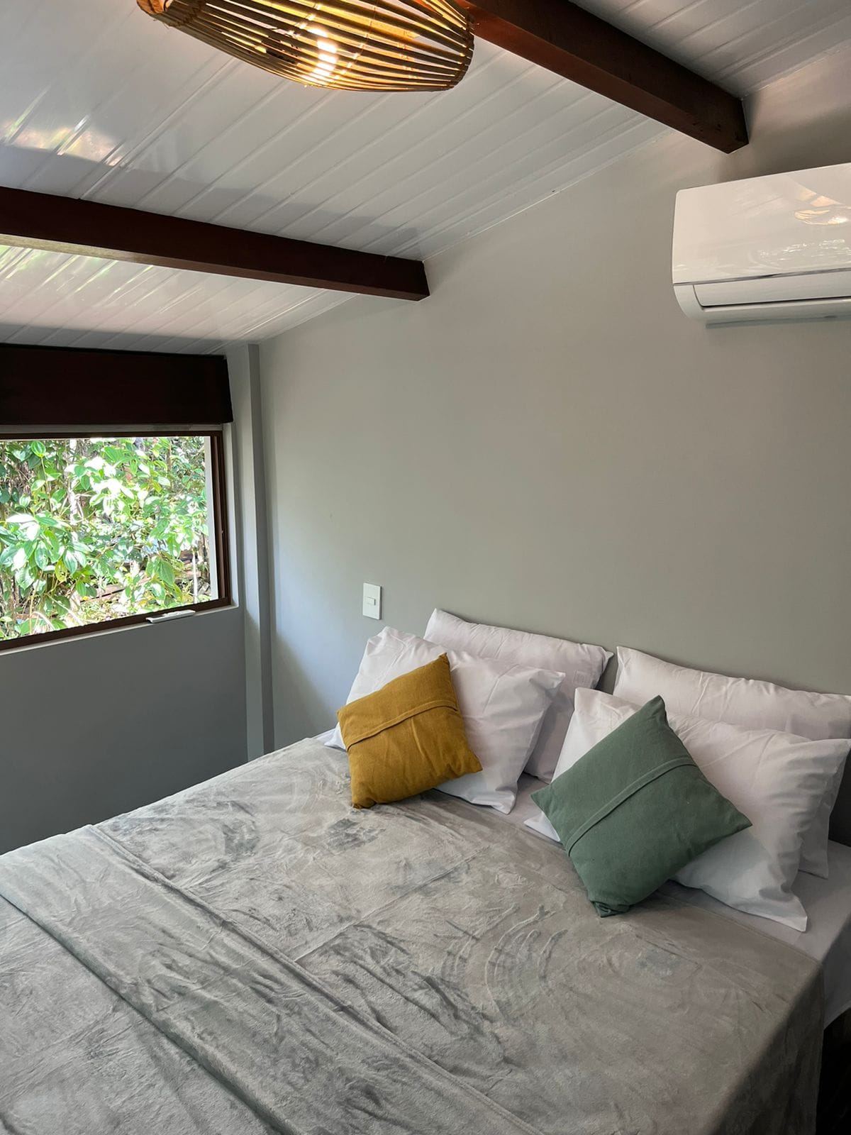 Habitación de un chalé de Itacaré Ecolodge con cama doble, aire acondicionado y ventana hacia el bosque