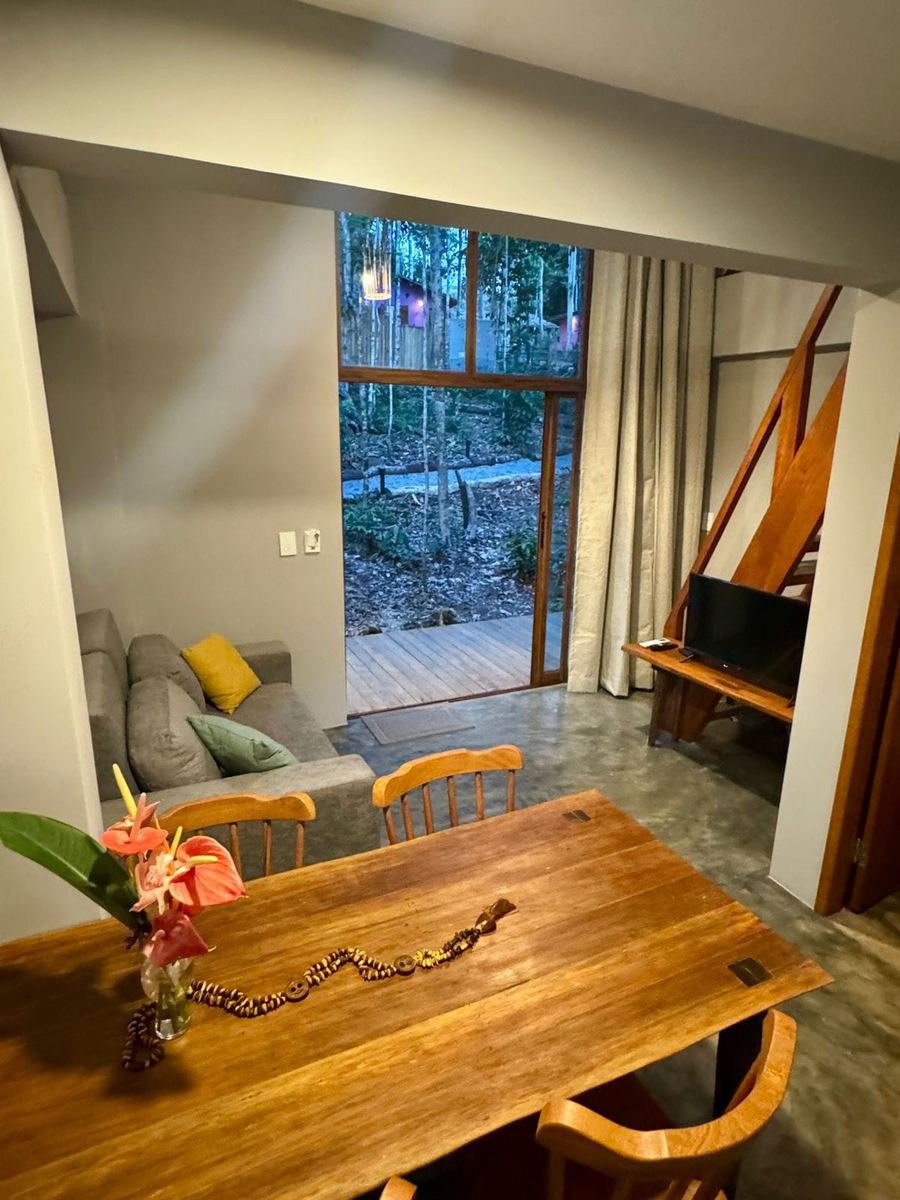 Sala de estar del chalé con sofá, mesa de madera y puerta de vidrio hacia el bosque